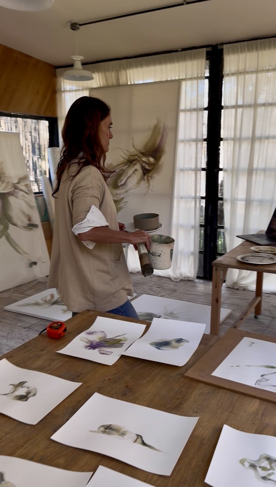Works on paper laid out on a long wooden table in the studio
